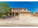 Two-story tan home features a three-car garage, desert landscaping, and a light-colored tile roof at 26272 N 73Rd Dr, Peoria, AZ 85383
