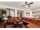 Spacious living room featuring a plush brown sectional sofa, ceiling fan, and open access to kitchen at 26272 N 73Rd Dr, Peoria, AZ 85383
