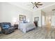 Spacious bedroom with tray ceiling, wood-look flooring, a ceiling fan, and a comfortable armchair at 2630 E Lovebird Ln, Gilbert, AZ 85297