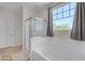 Bathroom featuring a combined tub and shower with glass enclosure and a window with leafy green views at 27053 N 172Nd Ln, Surprise, AZ 85387