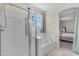 Bathroom featuring a bathtub with shower, a glass door enclosure, and natural light from an exterior window at 27053 N 172Nd Ln, Surprise, AZ 85387
