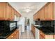Galley kitchen with wood cabinetry, granite countertops, and stainless steel appliances at 330 W Maryland Ave # 207, Phoenix, AZ 85013
