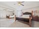 Bedroom with carpet, ceiling fan, and large mirror reflecting a carved wood frame bed and a nightstand at 4822 N 63Rd Ln, Phoenix, AZ 85033