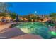 Nighttime pool view showcasing a relaxing lounge area, rock features, and subtle lighting creating an inviting atmosphere at 8447 W Tether Trl, Peoria, AZ 85383