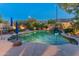 Charming pool featuring rock accents, ambient lighting, and lush greenery, creating a serene and inviting outdoor space at 8447 W Tether Trl, Peoria, AZ 85383