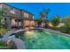 Nighttime view of a sparkling pool, lush landscaping, and inviting lounge areas, perfect for evening relaxation and entertainment at 8447 W Tether Trl, Peoria, AZ 85383