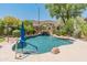Relaxing backyard pool area with beautiful rock waterfall feature and blue umbrella at 8447 W Tether Trl, Peoria, AZ 85383