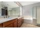 Bathroom showcasing a double sink vanity, a soaking tub, a glass block window, and a separate shower stall at 8758 W Hayward Ave, Glendale, AZ 85305