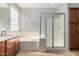 Clean bathroom with a separate shower and tub, complemented by wood cabinets and a frosted window for privacy at 8758 W Hayward Ave, Glendale, AZ 85305