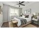 Stylishly furnished bedroom features a ceiling fan, window with white curtains, and a cozy bench at the foot of the bed at 8758 W Hayward Ave, Glendale, AZ 85305