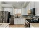 Modern kitchen with stainless steel appliances, white cabinets, stylish backsplash, and ample counter space at 8758 W Hayward Ave, Glendale, AZ 85305