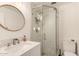 Bright bathroom features a modern sink, round mirror, and glass door shower at 10794 S Coolwater Dr, Goodyear, AZ 85338