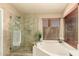 Bright bathroom showcasing a soaking tub and glass-enclosed shower with tile surround and natural lighting at 10794 S Coolwater Dr, Goodyear, AZ 85338
