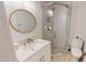 Well lit bathroom with stand up shower, wood cabinets and fixtures with a round mirror at 10794 S Coolwater Dr, Goodyear, AZ 85338