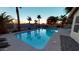 Backyard pool with palm trees, waterfall feature, and basketball hoop for outdoor entertainment at 10794 S Coolwater Dr, Goodyear, AZ 85338