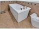 A freestanding white bathtub with vintage fixtures in a neutral-toned bathroom at 12682 N 80Th Pl, Scottsdale, AZ 85260
