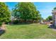 Expansive backyard featuring lush green grass, mature trees, and an outdoor fireplace for entertaining at 13034 W Krall Ct, Glendale, AZ 85307