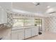 Kitchen features neutral countertops, white cabinets, floral wallpaper, tile floors, and a sink at 132 W Wood Dr, Phoenix, AZ 85029