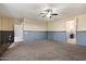 Open-concept living room offering modern ceiling fan, plush carpeting, and entrance to a bathroom at 15844 W Lisbon Ln, Surprise, AZ 85379