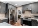 Well-equipped kitchen showcasing stainless steel appliances, ample gray cabinetry, and terracotta tile flooring at 1743 W Acoma Dr, Phoenix, AZ 85023