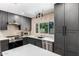 Modern kitchen features dark gray cabinets, stainless steel appliances, quartz countertops, and a bright window view at 1743 W Acoma Dr, Phoenix, AZ 85023