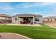 Backyard view with a covered patio, BBQ, seating area, and green synthetic grass at 17721 W Sandalwood Dr, Goodyear, AZ 85338