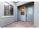 Exterior view of a front entrance with brick pavers and a gray door framed by textured walls and windows at 17721 W Sandalwood Dr, Goodyear, AZ 85338