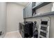 Practical laundry room with sleek black washer and dryer, storage cabinets, and shelving for an organized space at 17721 W Sandalwood Dr, Goodyear, AZ 85338