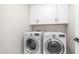 Functional laundry room with modern washer and dryer, as well as overhead cabinets for storage at 22706 N 17Th St, Phoenix, AZ 85024