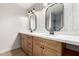 Stylish bathroom featuring double sinks, wood cabinets, modern fixtures, and patterned wallpaper at 3021 W Angela Dr, Phoenix, AZ 85053