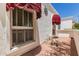 An exterior detail showing white stucco, a red awning, decorative window and paver patio at 38 E Calavar Rd, Phoenix, AZ 85022