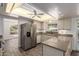 Updated kitchen offering stone counters, stainless steel fridge, white cabinetry, and an eating area at 38 E Calavar Rd, Phoenix, AZ 85022