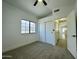 Bedroom featuring a large window, neutral carpet, closet with sliding doors, ceiling fan with light and hallway entrance at 4050 E Agave Rd, Phoenix, AZ 85044