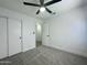 Bright bedroom featuring a neutral carpet, closet with sliding doors, ceiling fan with light and hallway entrance at 4050 E Agave Rd, Phoenix, AZ 85044