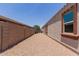 Side yard with rock cover to a brick wall with rear yard access at 41041 W Somers Dr, Maricopa, AZ 85138