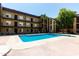 Community pool surrounded by tan apartment buildings with palm trees and clear blue sky at 461 W Holmes Ave # 350, Mesa, AZ 85210