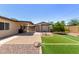 Spacious backyard with artificial grass, stone pavers, desert plants, and a covered patio at 538 E Estevan Ave, Apache Junction, AZ 85119