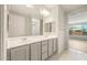 Bathroom with double vanity, white cabinetry, and a well-lit mirror at 7661 W Meadowlark Way, Florence, AZ 85132