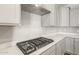 Close-up of gas cooktop with stainless steel vent hood and modern light gray cabinetry at 7661 W Meadowlark Way, Florence, AZ 85132