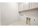 Functional laundry room with tile floor, overhead cabinets and utility connections in a neutral color scheme at 7661 W Meadowlark Way, Florence, AZ 85132