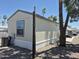Exterior view of the mobile home, surrounded by palm trees and natural desert landscaping at 7920 W Glendale Ave # 39, Glendale, AZ 85303