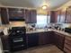 Functional kitchen with dark wood cabinets, black appliances, and a window over the sink at 7920 W Glendale Ave # 39, Glendale, AZ 85303