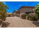 Enclosed backyard with gravel landscaping, flowering bushes, and a covered patio at 1282 N Banning St, Gilbert, AZ 85234