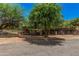 A tranquil property featuring mature trees, horse stables and fencing under a beautiful blue sky at 1282 N Banning St, Gilbert, AZ 85234