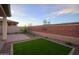 Manicured backyard featuring a strip of artificial turf, desert landscaping, and a brick perimeter wall at 13195 N 145Th Ln, Surprise, AZ 85379