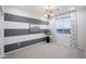 A bedroom with gray and white striped walls, modern chandelier, large windows, and neutral carpet at 13195 N 145Th Ln, Surprise, AZ 85379