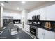 Kitchen showcases white cabinets, stainless steel appliances, dark countertops and a black tile backsplash at 13195 N 145Th Ln, Surprise, AZ 85379