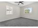 This bedroom is well-lit with a ceiling fan, two windows, and neutral gray carpet at 1367 E Mitchell Dr, Phoenix, AZ 85014