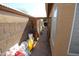 This side yard is narrow and features gravel, dirt, and a wooden walkway at 16251 N 91St Dr, Peoria, AZ 85382