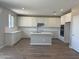 Bright kitchen features white cabinets, quartz countertops, stainless steel appliances, an island, and a herringbone backsplash at 18351 W Patrick Ln, Surprise, AZ 85387